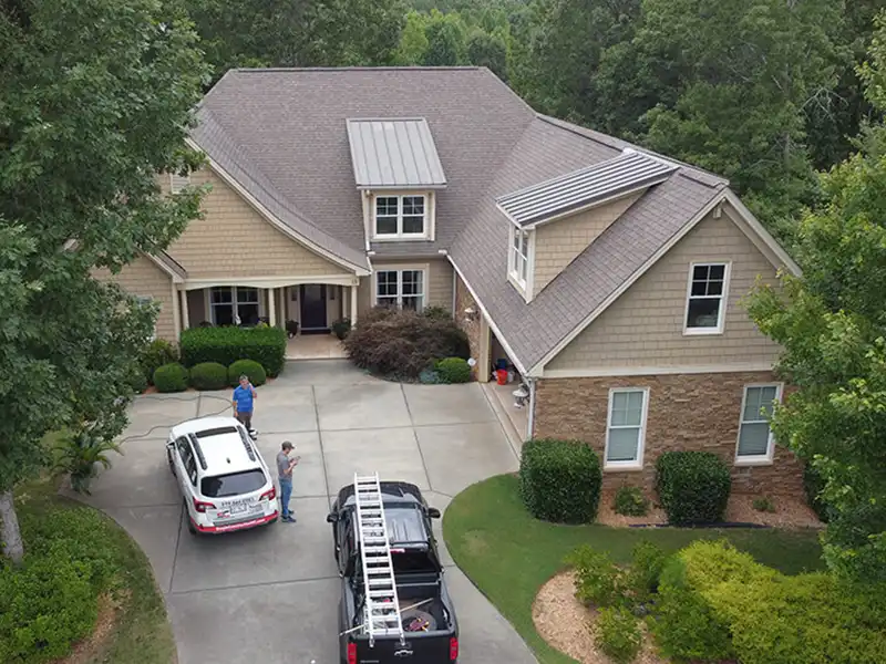 Large mid-class home with a brown shingle roof and some Simple Construction crew members and work trucks parked in front